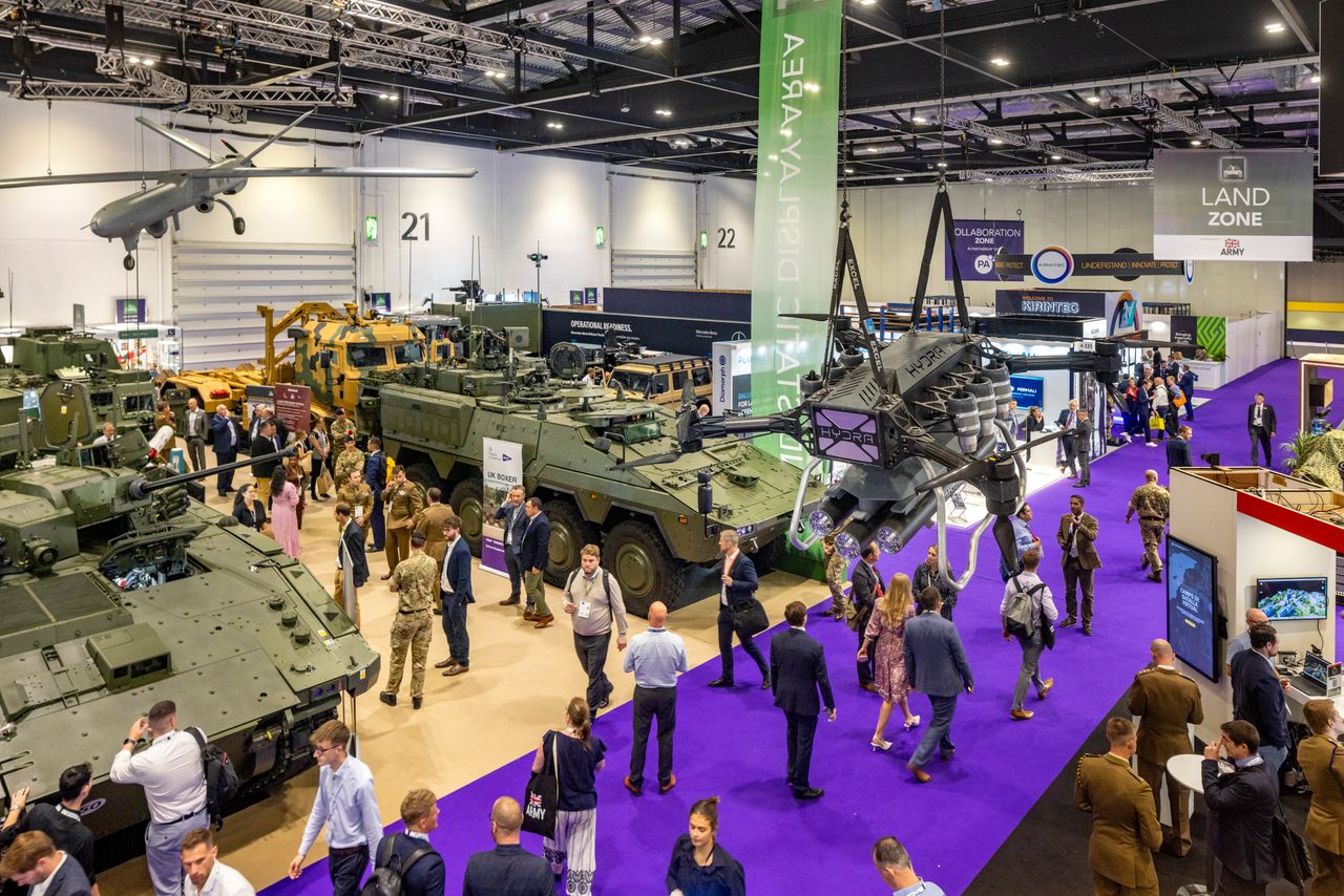 The bustling exhibition floor at DSEI 2025 filled with state-of-the-art military vehicles and displays.