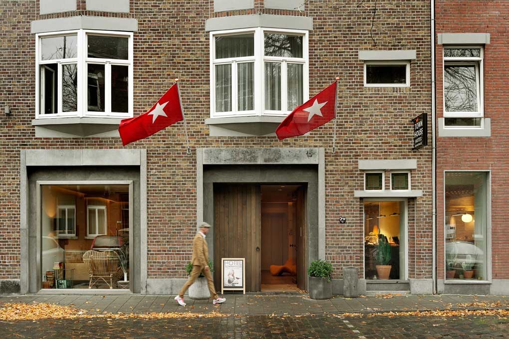a man walking past a building with flags